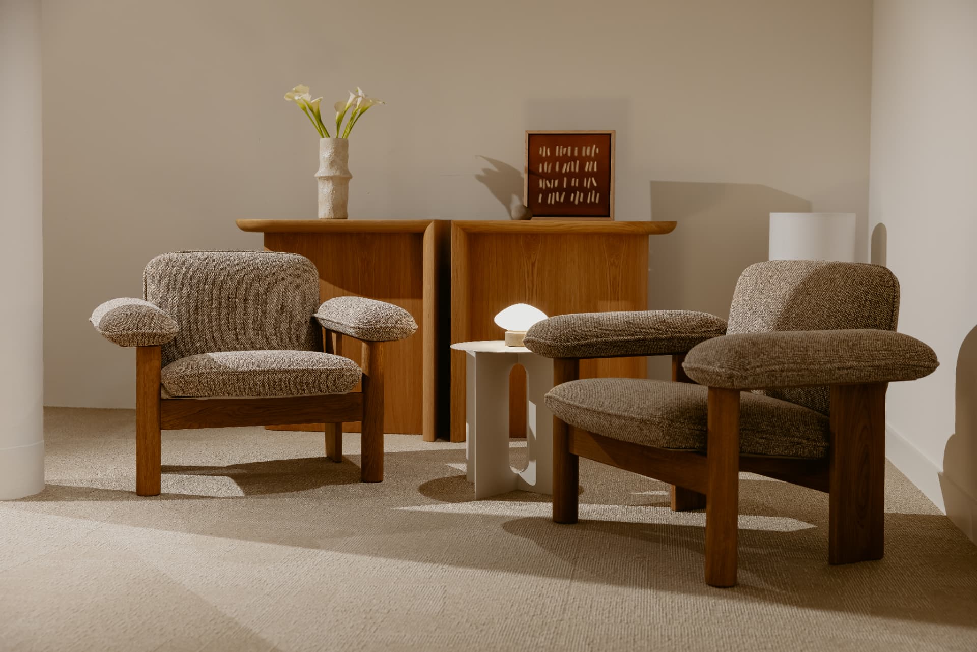 Two bouclé armchairs and a side table in a bright space