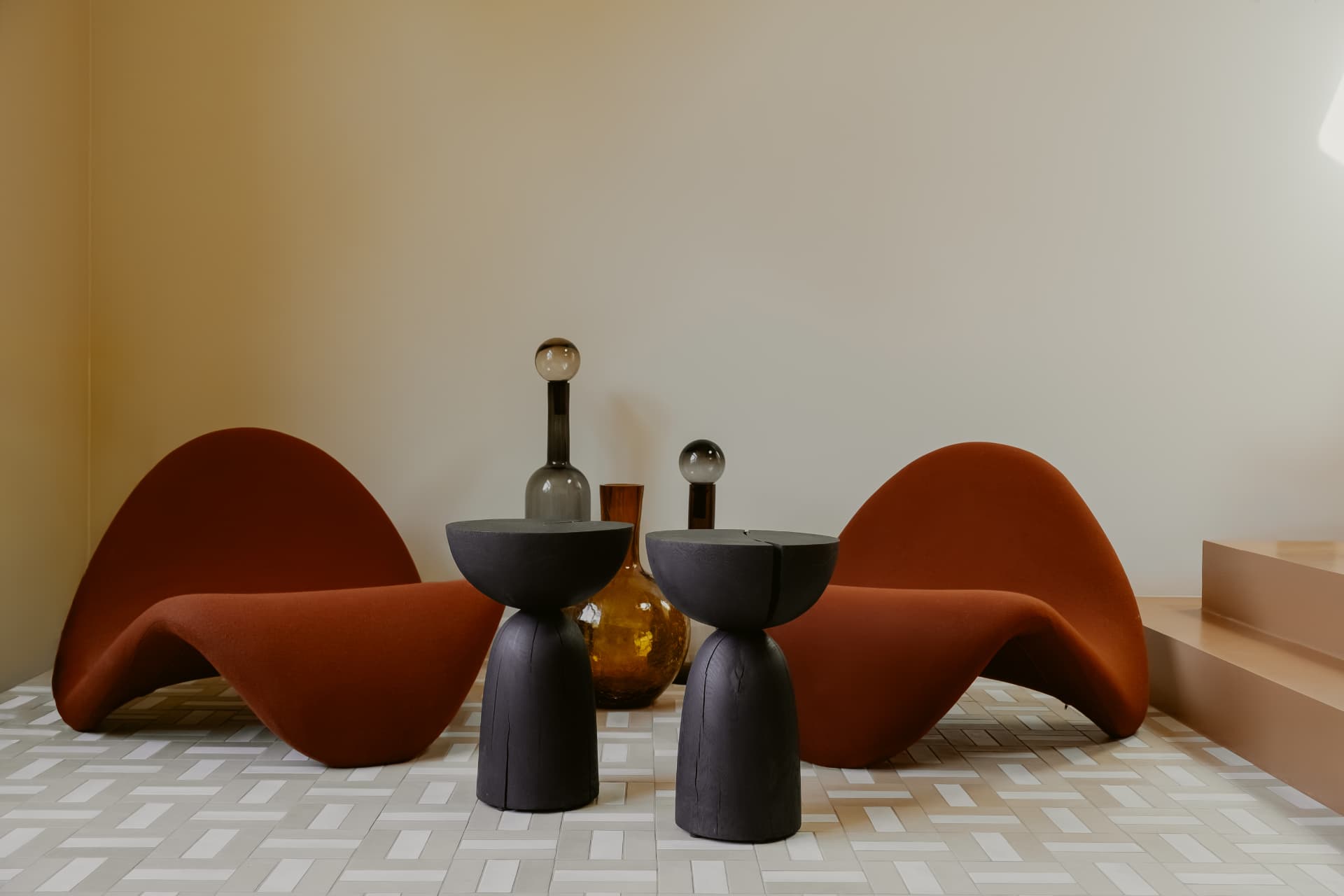 Two terracotta armchairs on a geometric mosaic floor in the Enky space