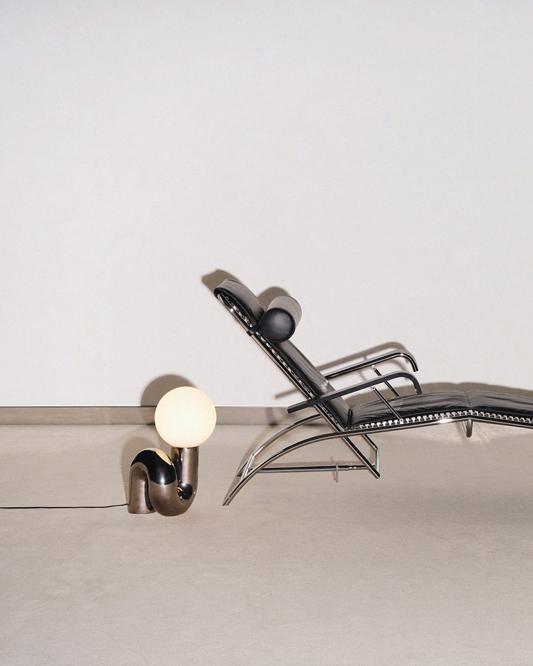 Black leather lounge chair and chrome spherical lamp