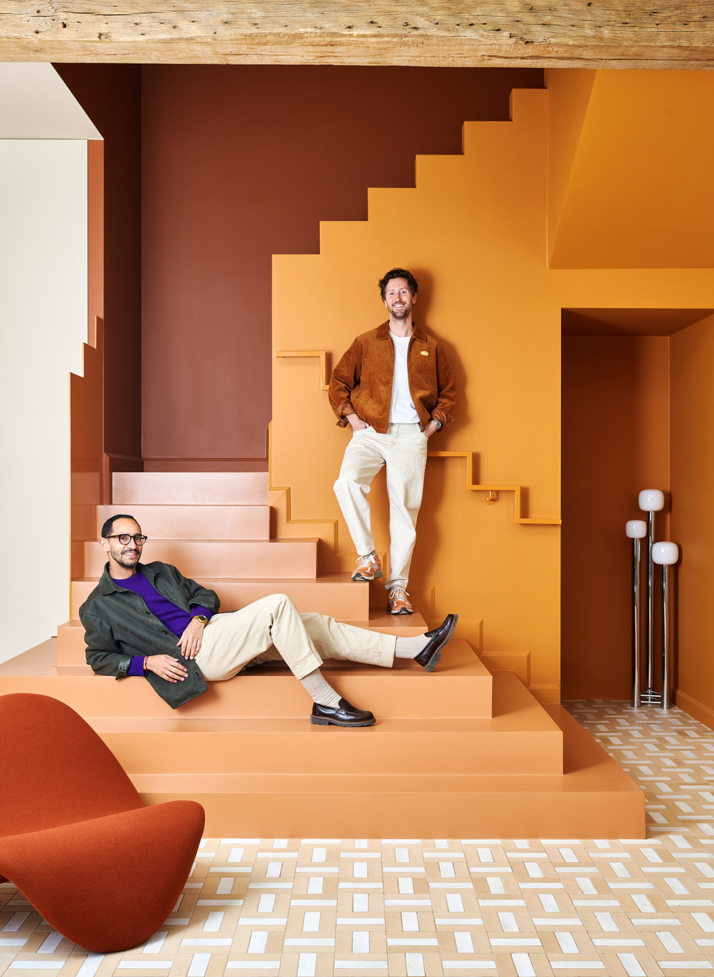 Two designers on a sculptural staircase in terracotta tones